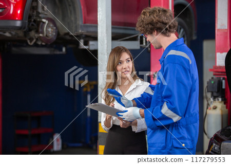 Man garage worker and woman customer talking to discuss details of car repairs. Man garage worker and woman customer talking to discuss details of car repairs. 117279553