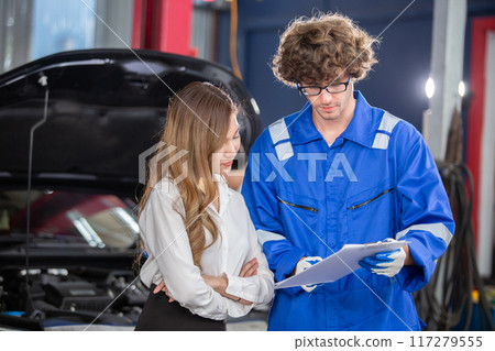 Man garage worker and woman customer talking to discuss details of car repairs.  117279555