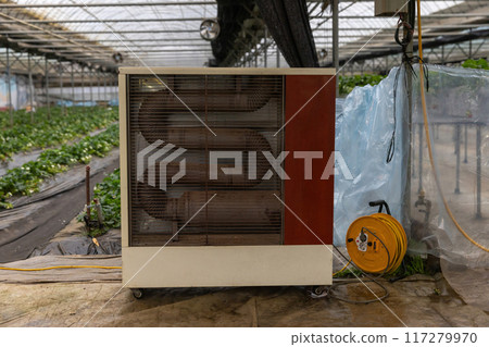 Heater in greenhouse with seedlings of plants 117279970