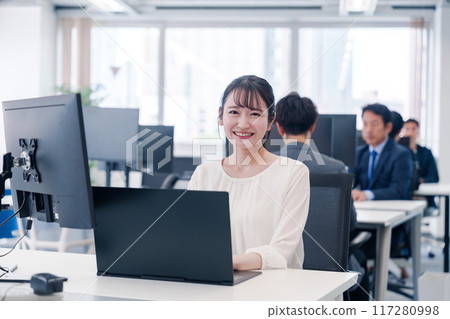 A young woman smiling and working at her desk in the office A young woman smiling and working at her desk in the office 117280998