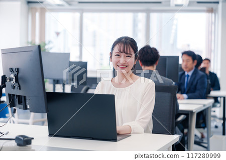 A young woman smiling and working at her desk in the office A young woman smiling and working at her desk in the office 117280999
