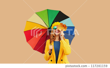 Autumn outfit, beautiful smiling young woman holds yellow maple leaves with colorful umbrella Autumn outfit, beautiful smiling young woman holds yellow maple leaves with colorful umbrella 117281159