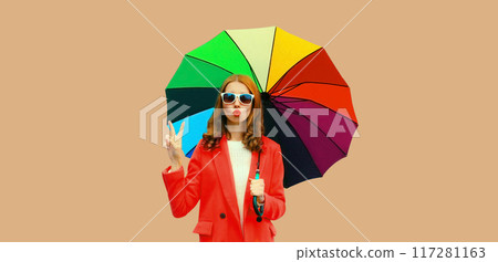 Autumn color style outfit, stylish young woman posing with colorful umbrella blowing a kiss Autumn color style outfit, stylish young woman posing with colorful umbrella blowing a kiss 117281163