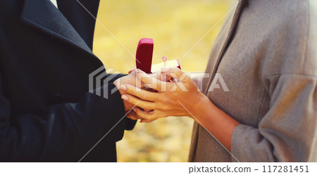 Love, relationships, engagement, wedding - man proposes woman to marry, holds red box ring in hands Love, relationships, engagement, wedding - man proposes woman to marry, holds red box ring in hands 117281451