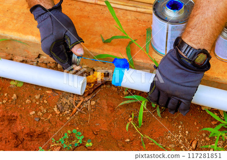Plumbing contractor installing glue PVC pipes to lay water line 117281851