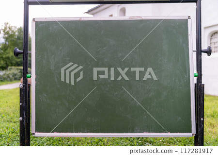 A chalkboard is positioned on grass, covered in scribbles and marks 117281917
