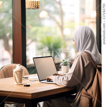 Arab woman in hijab using blank screen laptop in cafe or coworking space, remote work concept Arab woman in hijab using blank screen laptop in cafe or coworking space, remote work concept 117282793