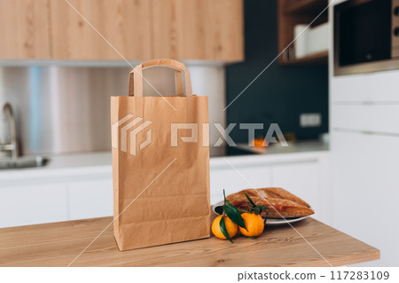 Food craft bag on the wooden table counter in the kitchen. Delivery in any weather around the clock to the client. Fast food eco packaging with big breakfast or diner set 117283109