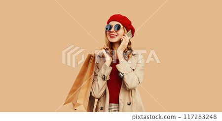 Autumn portrait of happy smiling young woman with shopping bag calling on mobile phone Autumn portrait of happy smiling young woman with shopping bag calling on mobile phone 117283248
