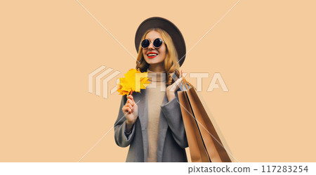 Autumn color style outfit, portrait of beautiful young woman with shopping bag, yellow maple leaves Autumn color style outfit, portrait of beautiful young woman with shopping bag, yellow maple leaves 117283254