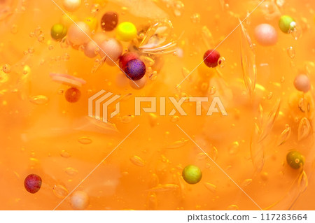 Colorful gel texture, clear skincare cream with bubbles and decorative figurines background, transparent beauty serum, colored cosmetic product close up 117283664