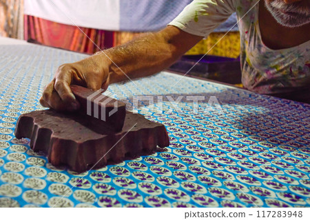 Artisan hand stamping patterns in ink with block on traditional Indian textiles 117283948