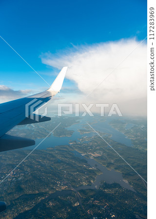 Aircraft flying in sunset. Clouds, rainbow and a wing of airbus from the airplane window 117283969