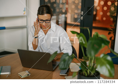 A Professional Woman Engaged in Work from a Modern Office Environment While Remote 117284334