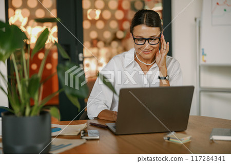 A Dedicated and Focused Professional Working Intently on a Laptop in a Modern Office Space A Dedicated and Focused Professional Working Intently on a Laptop in a Modern Office Space 117284341