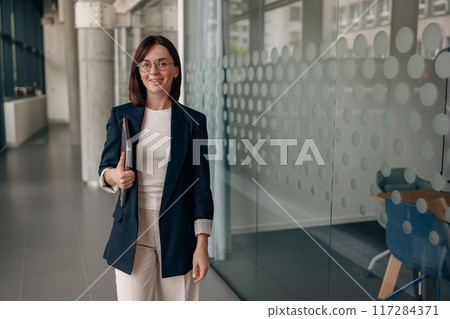A confident businesswoman is presenting technology in a modern office environment A confident businesswoman is presenting technology in a modern office environment 117284371