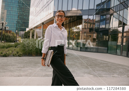 A Confident Young Professional Walking Through a Vibrant Urban Setting with Purpose 117284380