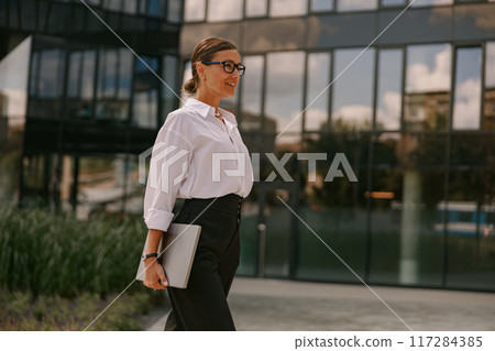 A Professional Woman confidently walking in a Modern Urban Environment, embodying success A Professional Woman confidently walking in a Modern Urban Environment, embodying success 117284385