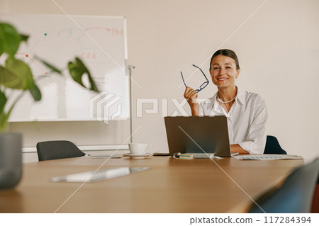 A Professional Woman Engaged in Work with a Laptop in a Contemporary Office Environment A Professional Woman Engaged in Work with a Laptop in a Contemporary Office Environment 117284394