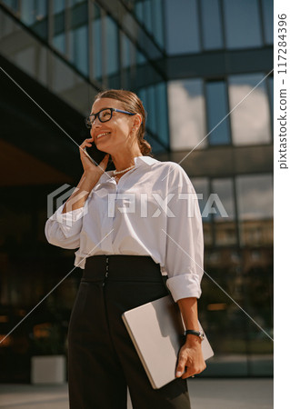 A professional office woman engaging in a phone conversation with confidence and poise A professional office woman engaging in a phone conversation with confidence and poise 117284396
