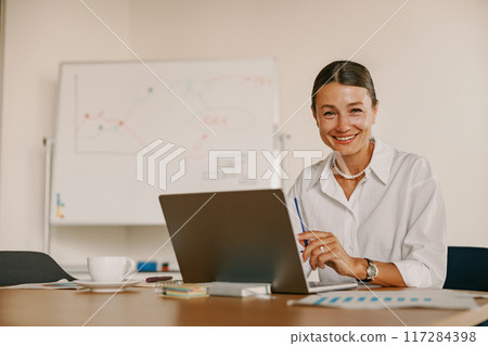 A Professional Woman Engaged in Her Work Within a Contemporary Office Environment A Professional Woman Engaged in Her Work Within a Contemporary Office Environment 117284398