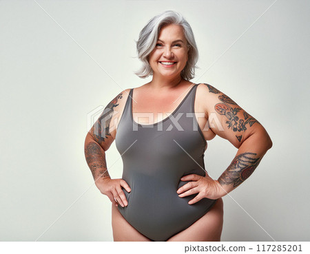 Confident Plus-Size Woman in Swimsuit against White Studio Background 117285201