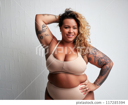Confident Plus-Size Woman in Swimsuit against White Studio Background Confident Plus-Size Woman in Swimsuit against White Studio Background 117285394