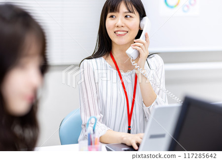 Woman picking up the phone in the office 117285642