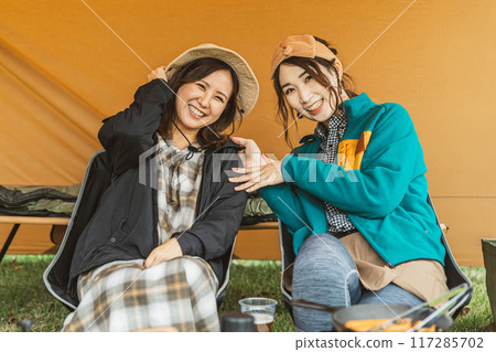 Asian female camper playing with friends in autumn winter camping outdoors Asian female camper playing with friends in autumn winter camping outdoors 117285702