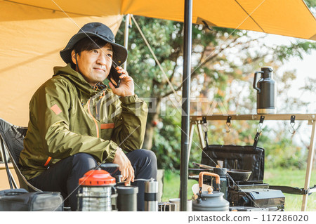 中年男性露營者在露營地使用智慧型手機(露營地/通話/談話) 中年男性露營者在露營地使用智慧型手機(露營地/通話/談話) 117286020