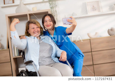 Caregiver young nurse woman taking a selfie with happy patient elderly woman with cheerful together. 117287431