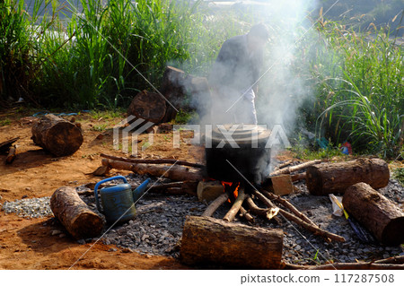 A outdoor steaming black pot on open fire on makeshift stove made of bricks and stones, surrounded by nature, as traditional Vietnamese cook banh tet for Tet holiday is culture culinary 117287508