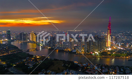 An aerial view of Ho Chi Minh City at sunset, vibrant colorful sky, the illuminated Landmark 81 skyscraper, the reflecting Saigon River in city lights of dynamic urban, awe cityscape 117287518