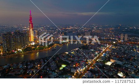 An aerial view of Ho Chi Minh City at sunset, vibrant colorful sky, the illuminated Landmark 81 skyscraper, the reflecting Saigon River in city lights of dynamic urban, awe cityscape 117287521