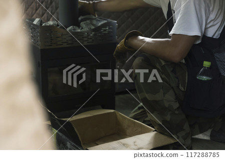 一名男子將桑拿石放在柴爐頂部，用於帳篷桑拿 117288785