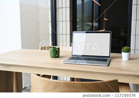 Laptop computer blank screen on wooden table in modern coffee shop 117289376
