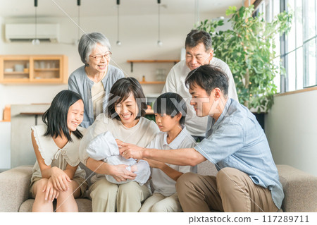 Mom and three generations family holding a baby on the sofa at home Mom and three generations family holding a baby on the sofa at home 117289711