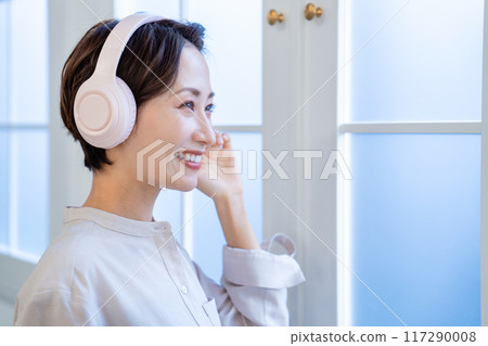 Middle-aged woman listening to music with headphones 117290008