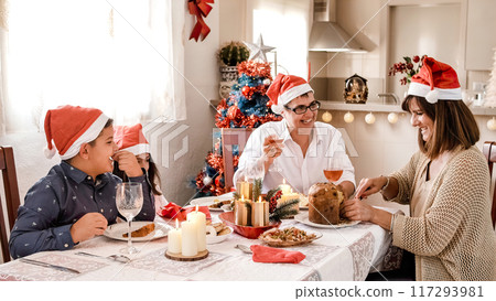 Mother cutting a christmas panettone with her family Mother cutting a christmas panettone with her family 117293981