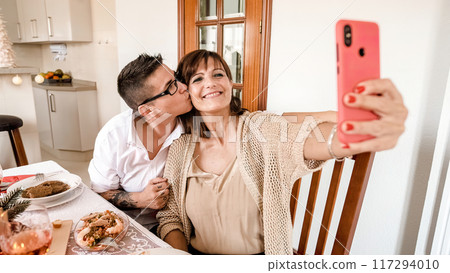 Lesbian couple kissing while taking a selfie during Christmas lunch 117294010
