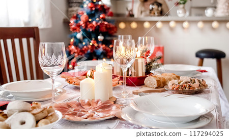 Christmas decorations on the table while a girl sets the table to eat 117294025