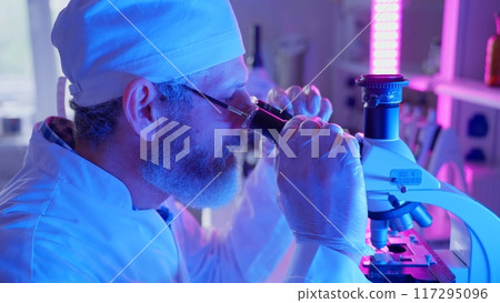 A chemist examines samples through a microscope, utilizing advanced technology in a vibrant laboratory setting. A chemist examines samples through a microscope, utilizing advanced technology in a vibrant laboratory setting. 117295096