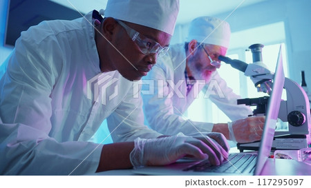 Chemists conduct research in a modern laboratory, utilizing advanced equipment and analyzing chemical reactions under striking purple neon lights. Chemists conduct research in a modern laboratory, utilizing advanced equipment and analyzing chemical reactions under striking purple neon lights. 117295097
