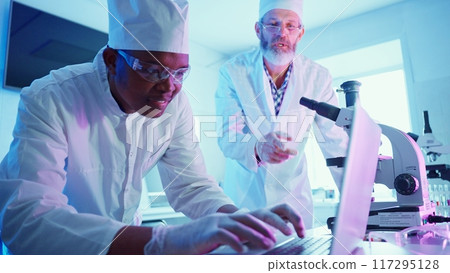 Two chemists work meticulously at a high-tech laboratory, analyzing data while using advanced equipment to advance their research in medicine and technology. Two chemists work meticulously at a high-tech laboratory, analyzing data while using advanced equipment to advance their research in medicine and technology. 117295128