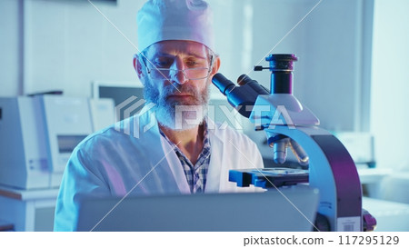 A chemist conducts analysis on samples with a microscope in a vividly lit laboratory showcasing innovation. A chemist conducts analysis on samples with a microscope in a vividly lit laboratory showcasing innovation. 117295129