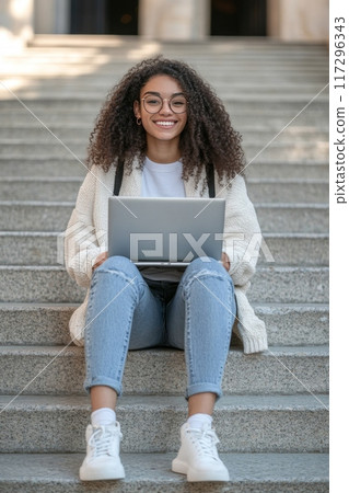 Cheerful Young Woman with Laptop Sitting on Stairs Outdoors 117296343