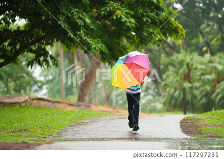 Child playing in rain. Kid jumping in puddle. 117297231