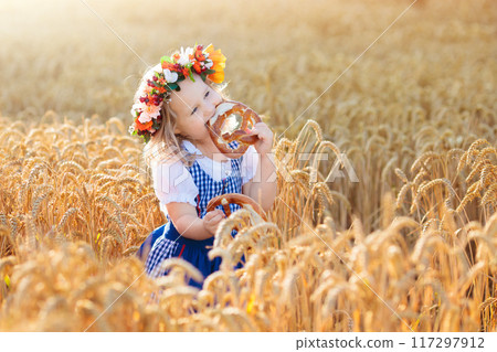 Child in wheat field with German bread Child in wheat field with German bread 117297912