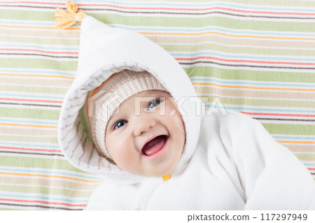 Little baby in winter hat on white bed Little baby in winter hat on white bed 117297949