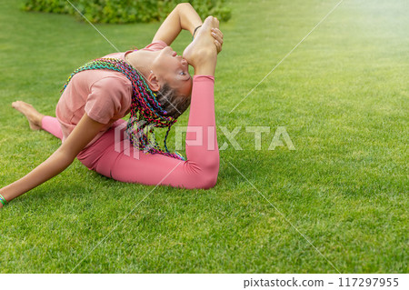 Flexible girl is performing gymnastic exercises outside. Flexible girl is performing gymnastic exercises outside. 117297955